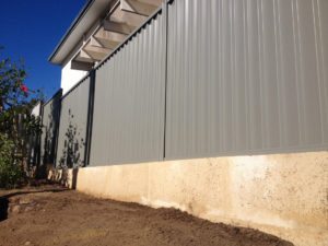 1 metre reconstituted limestone block retaing wall contractor and colorbond fence core drilled on top