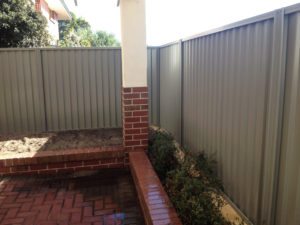 1 metre reconstituted limestone block retaing wall contractor and colorbond fence core drilled on top
