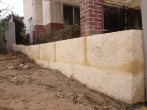 1 metre reconstituted limestone block retaing wall contractor and colorbond fence core drilled on top