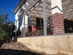 1 metre reconstituted limestone block retaing wall contractor and colorbond fence core drilled on top