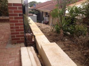 1 metre reconstituted limestone block retaing wall contractor and colorbond fence core drilled on top